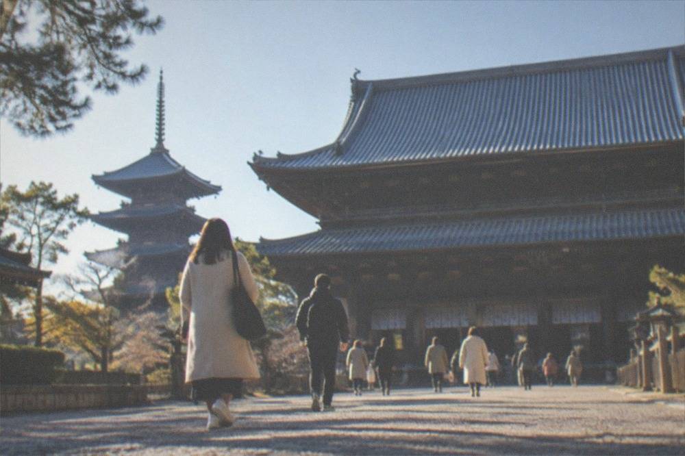 Visitors walking through To-ji temple grounds toward the Kondo main hall