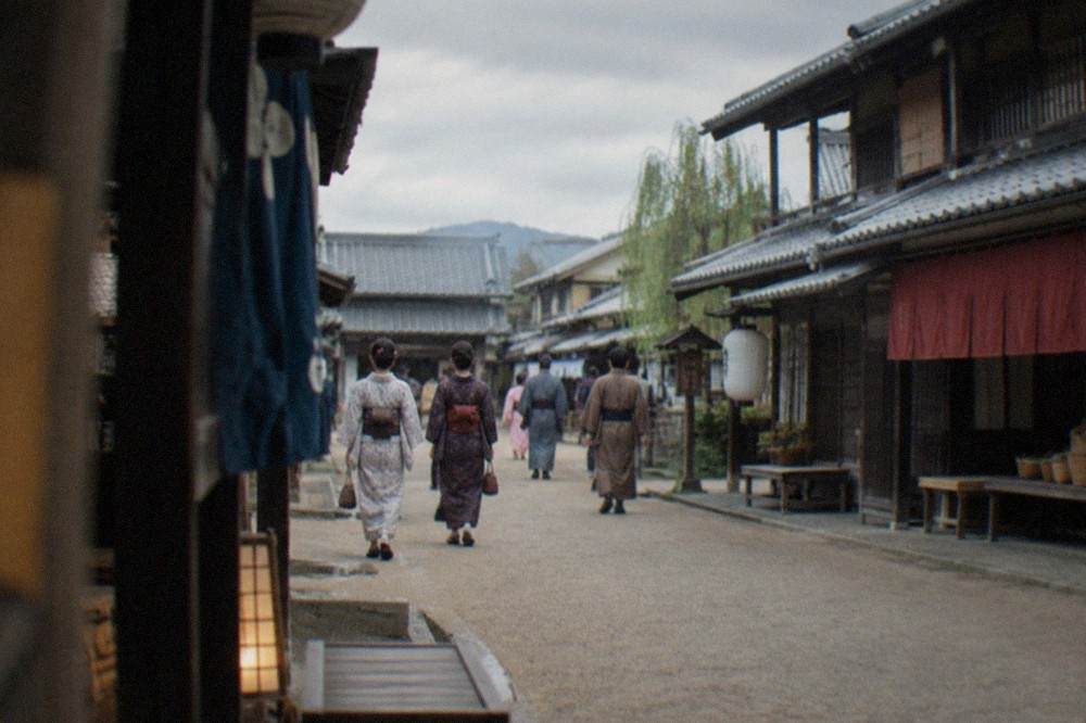 Visitors in period costume walking a recreated Edo town street at a film theme park
