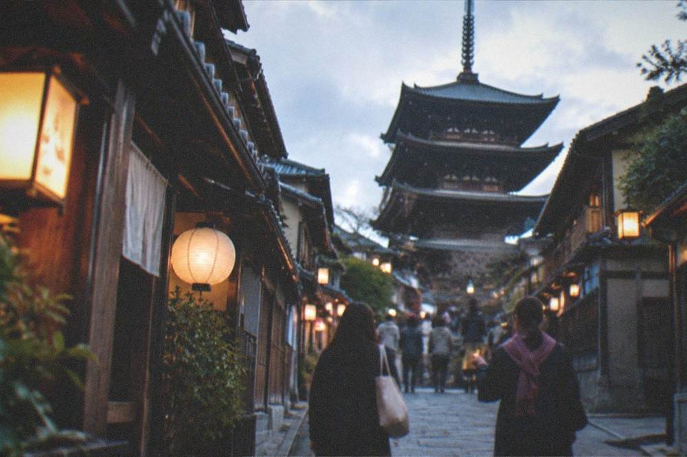 A local guide leading a small group of visitors along a lantern-lit Gion street in the evening