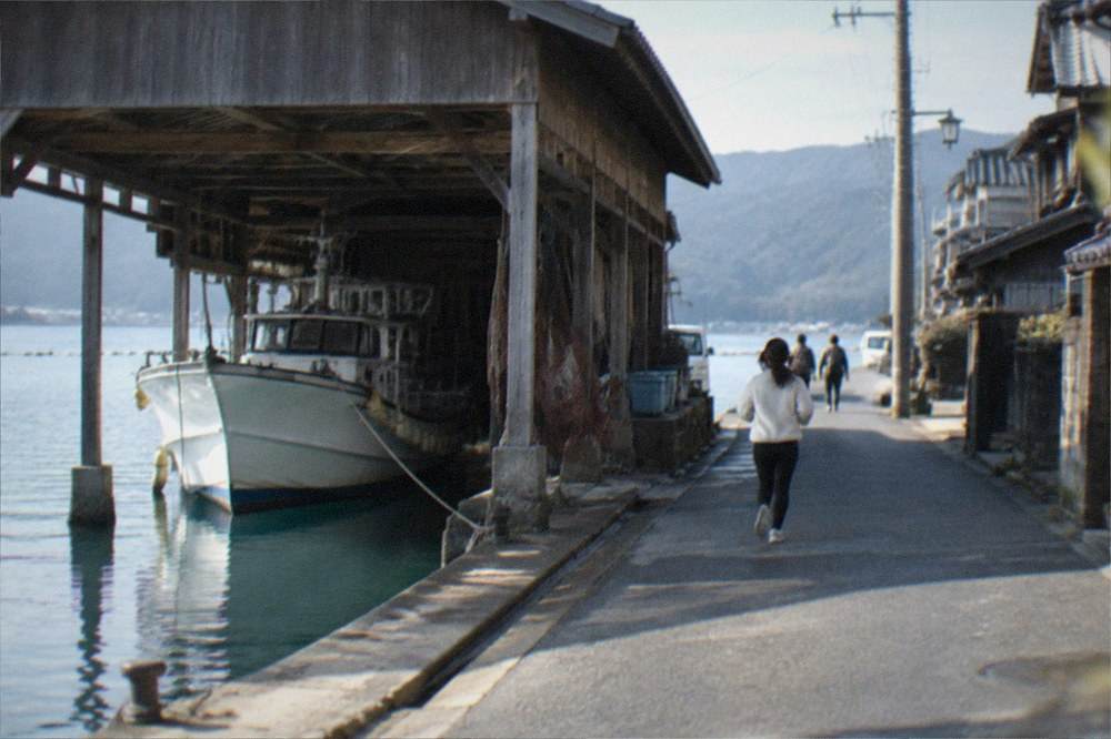A wooden boat shelter with a fishing vessel moored inside its open lower floor