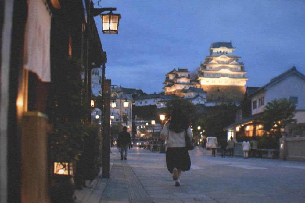 The illuminated castle keep seen from the station approach street after sunset