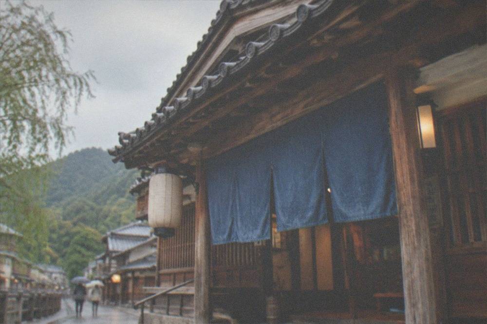 A traditional wooden public bathhouse exterior with tiled roof and noren curtain