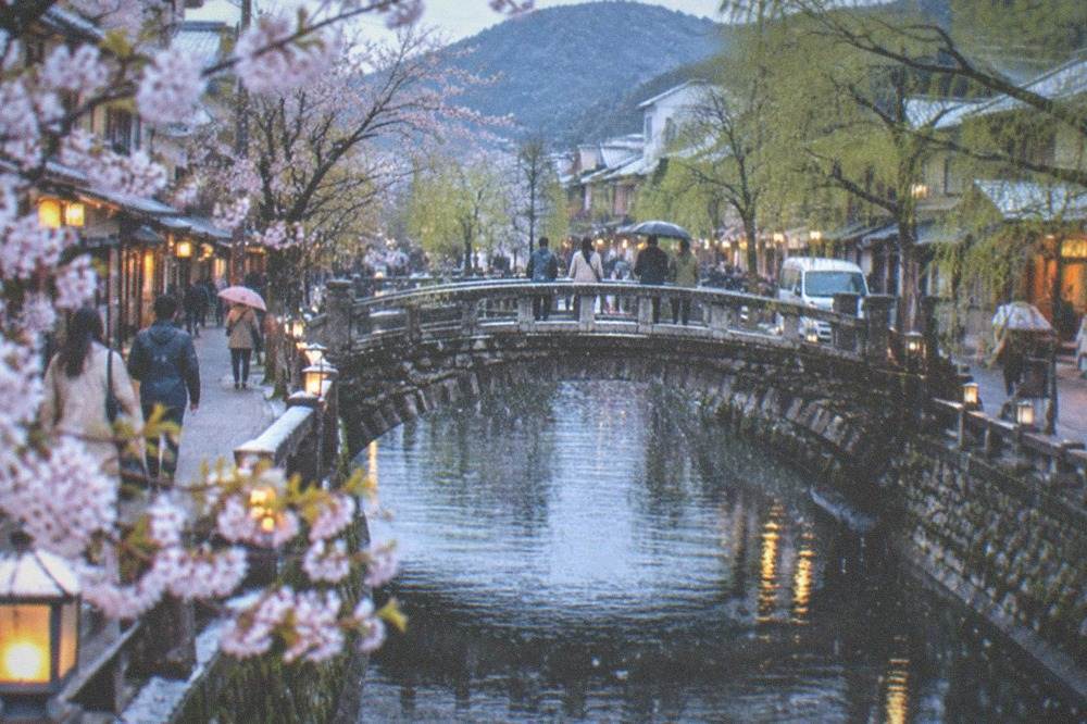 Snow falling on a stone bridge over a canal in a hot spring town
