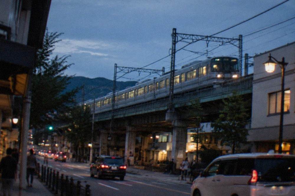 Commuter trains lined up on elevated tracks above a Japanese city street