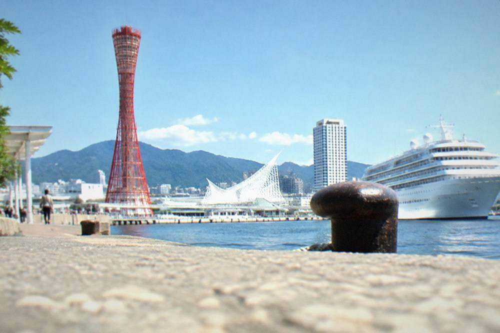 Red port tower and white cruise ship at a harbour park in Kobe