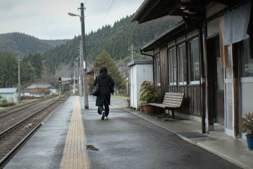 Quiet country rail station platform with forested hills behind it