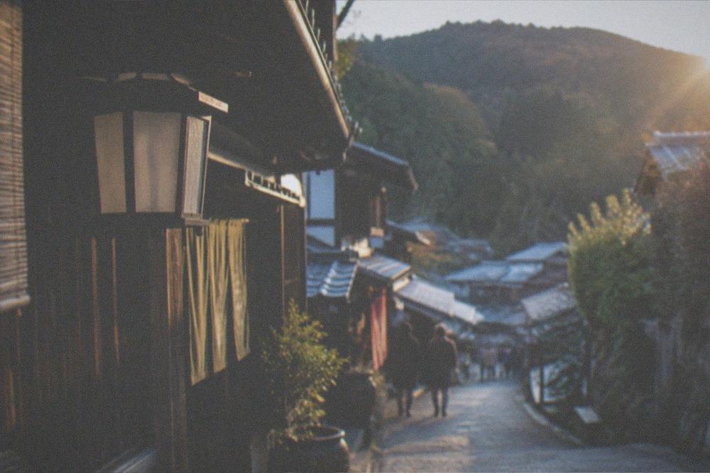 A mountain village street with traditional wooden buildings and forest slopes behind