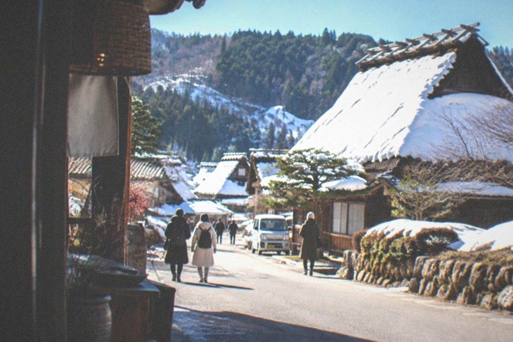 Thatched farmhouse roofs covered in deep snow under a clear winter sky