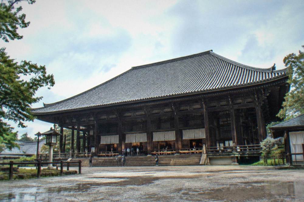 A vast wooden temple hall with a large tiled roof seen from across a courtyard