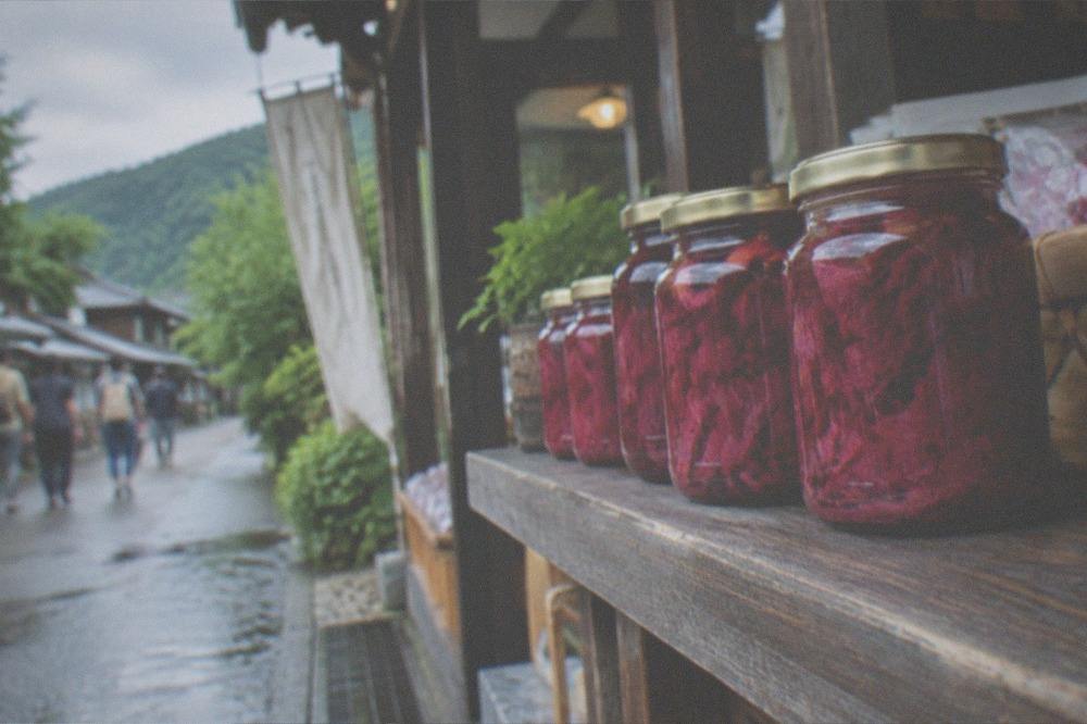Jars of bright pink pickled red shiso leaves on a wooden shop shelf