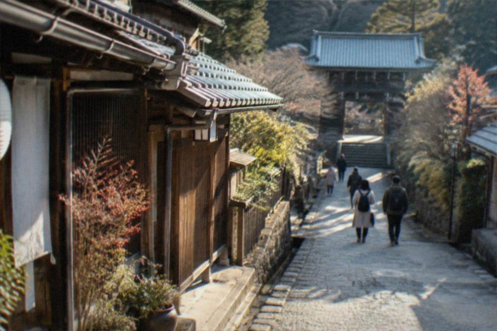 A quiet lane between wooden buildings leading up toward a temple gate in a mountain village