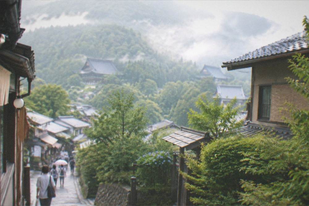 Morning mist lifting off a green valley with temple roofs visible among the trees