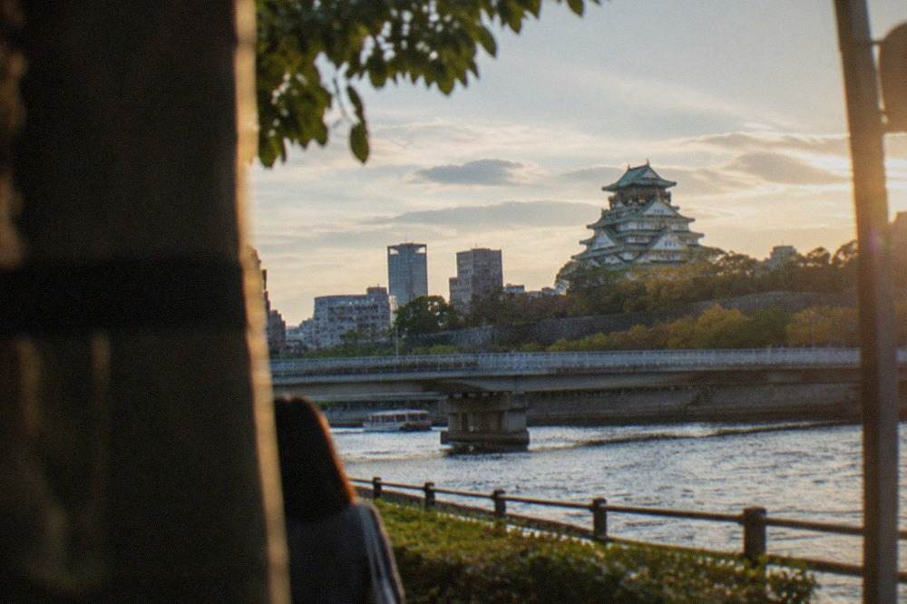 Osaka Castle rising above the city skyline with the Okawa river in the foreground