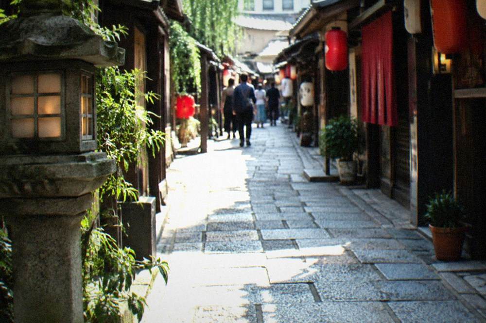 A stone-paved lantern-lit alley in Hozenji Yokocho with small restaurants on both sides