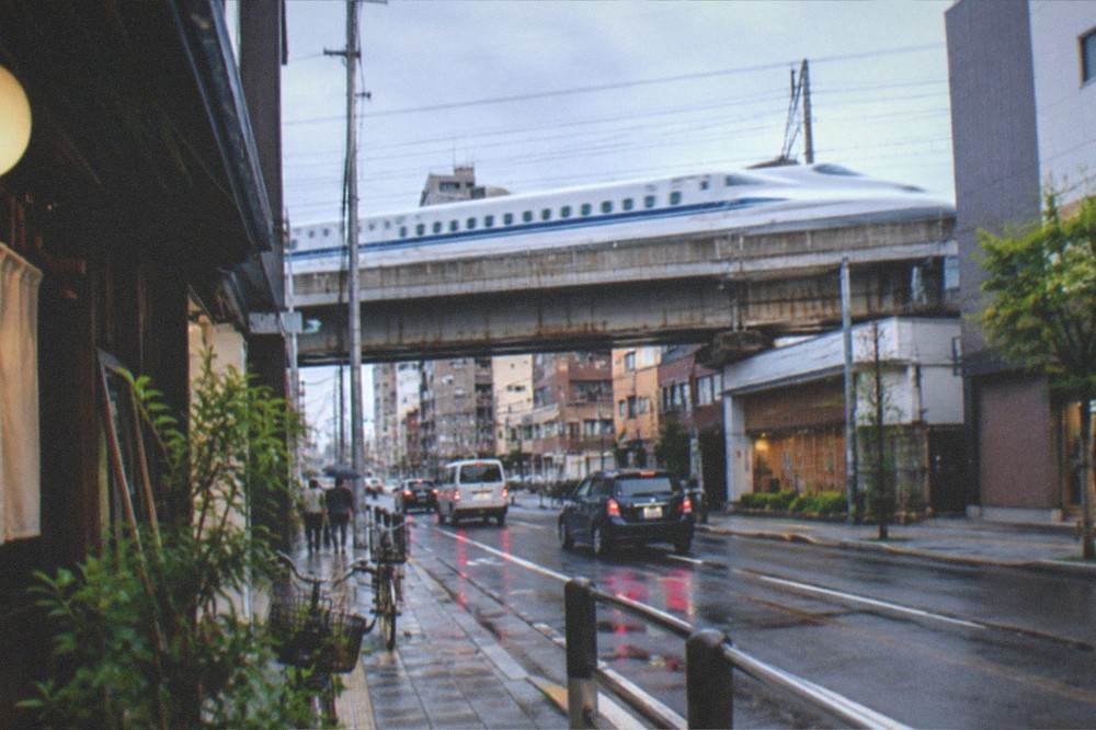 A bullet train passing at speed on an elevated track above city buildings