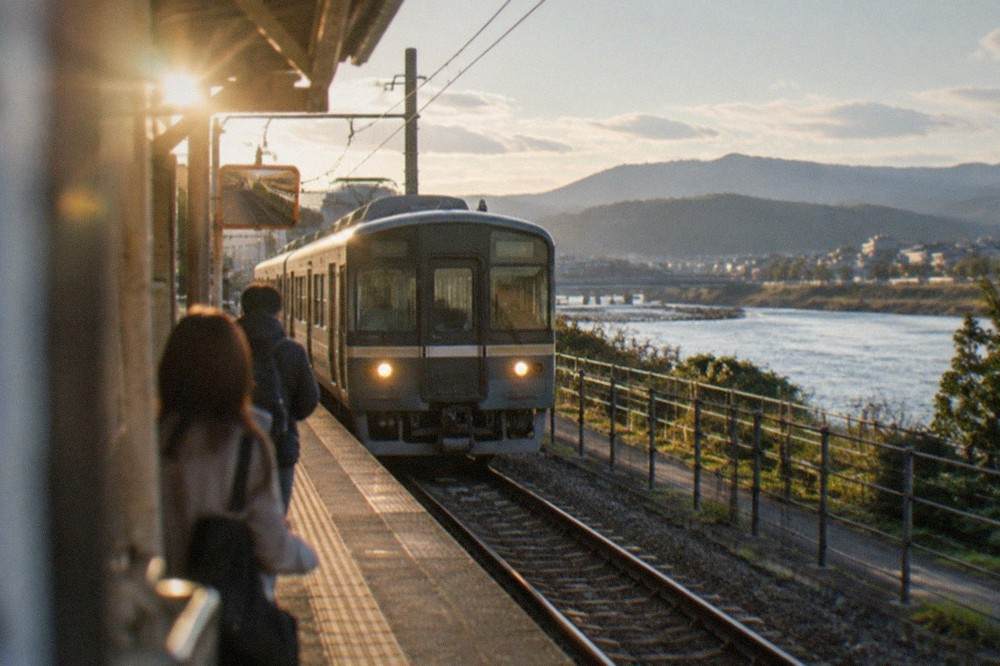 A local train arriving at a small riverside station platform in Uji