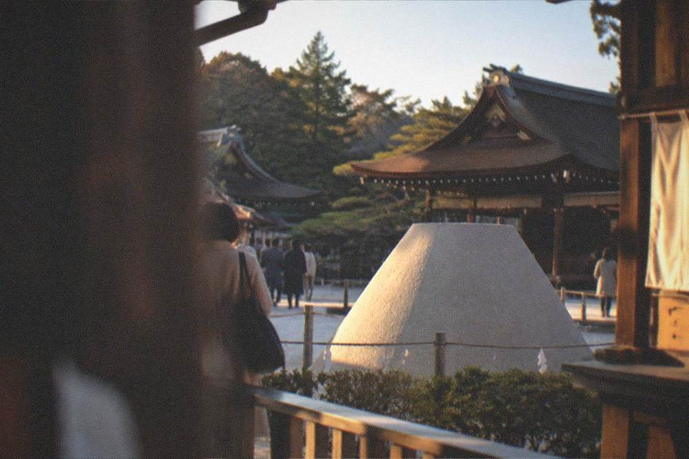 White sand cone and wooden shrine buildings at Kamigamo Shrine under a clear sky