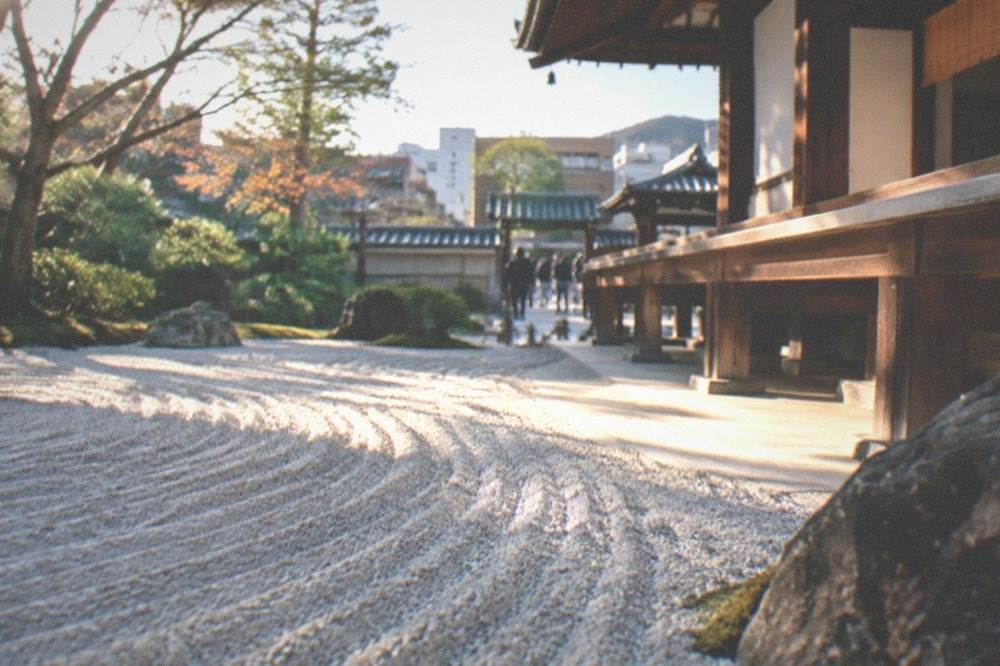A quiet garden with raked gravel and a wooden temple veranda in Kyoto
