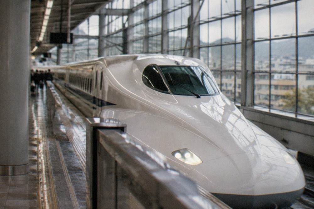 A high speed Shinkansen train waiting at a platform inside Kyoto Station's large glass hall