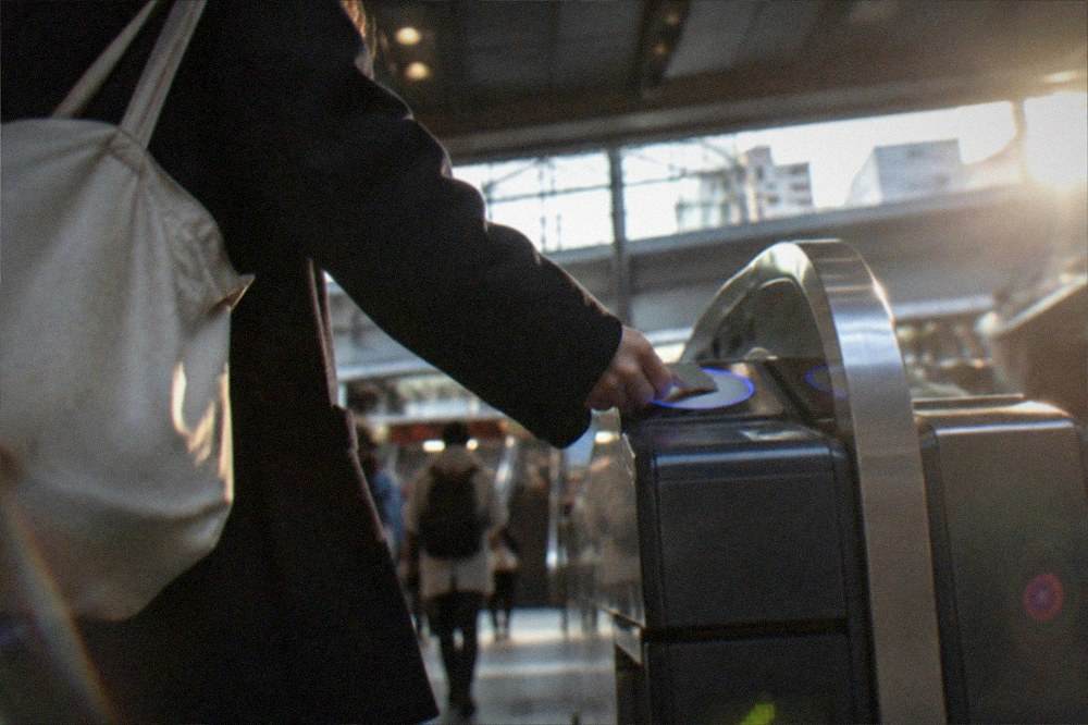 A visitor tapping a smart card on a ticket gate at a Kyoto subway station