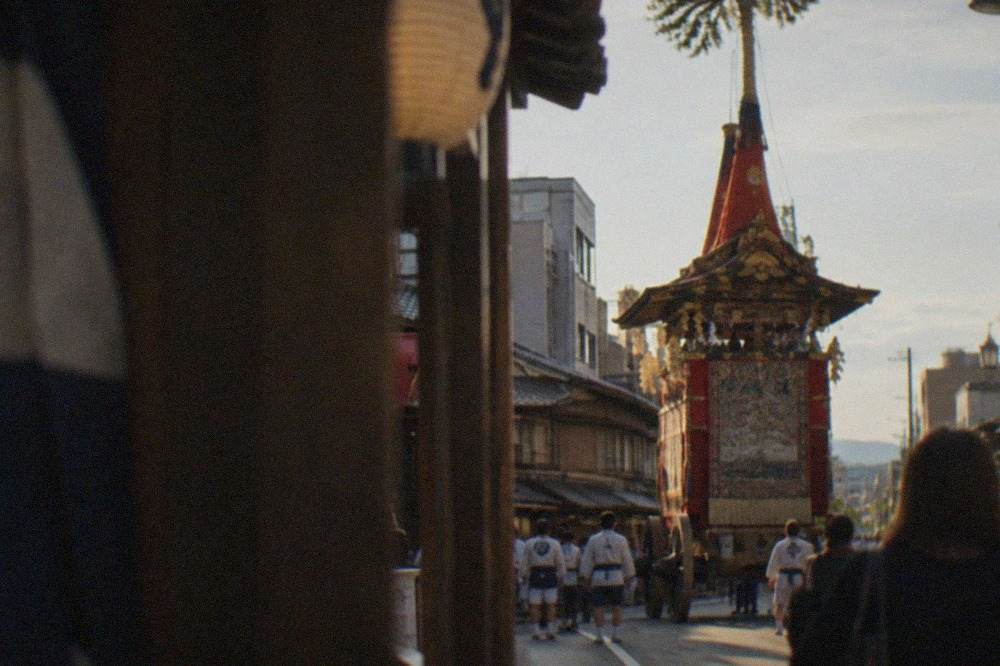 A tall decorated festival float standing on a Kyoto street in the evening