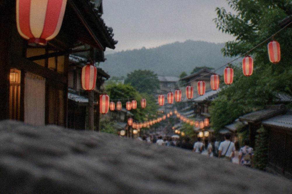 Rows of paper lanterns strung across a narrow street during a summer festival evening