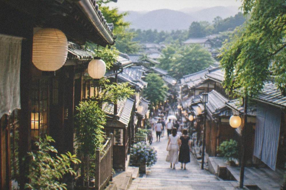 A traditional wooden Kyoto streetscape in summer with lanterns hanging from eaves