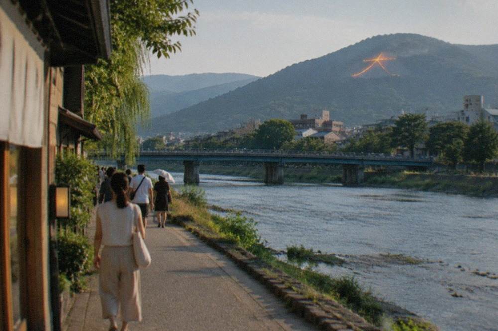 A giant fire character burning on a dark mountainside above the city lights of Kyoto
