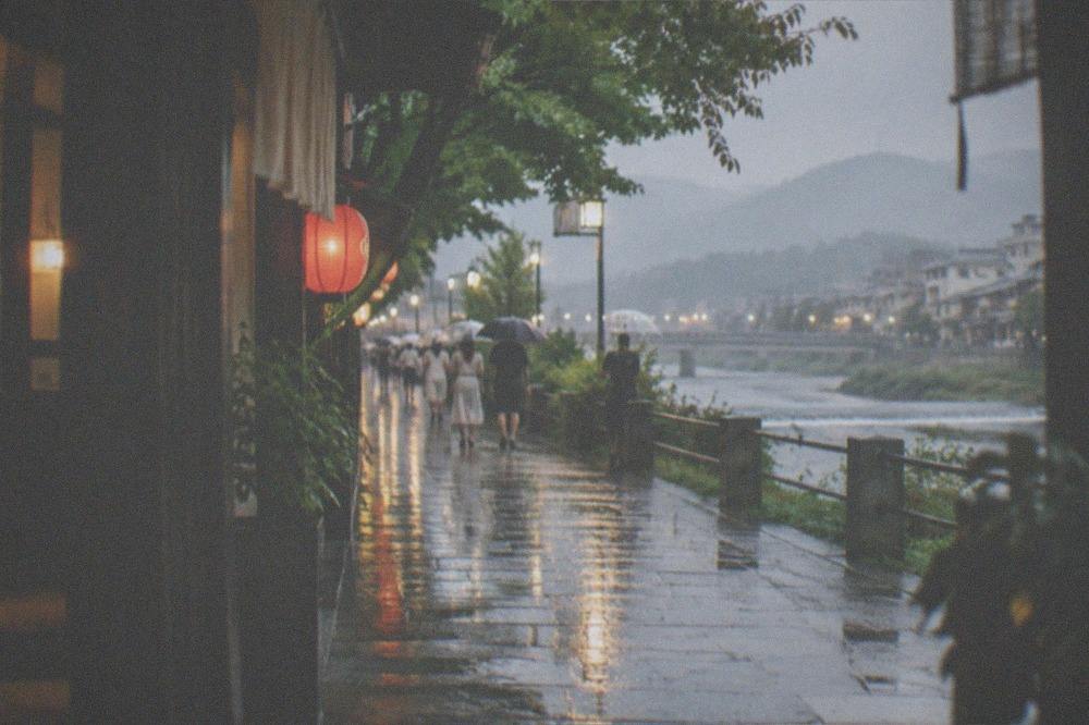 A rainy evening street in Kyoto with lanterns reflecting on wet pavement