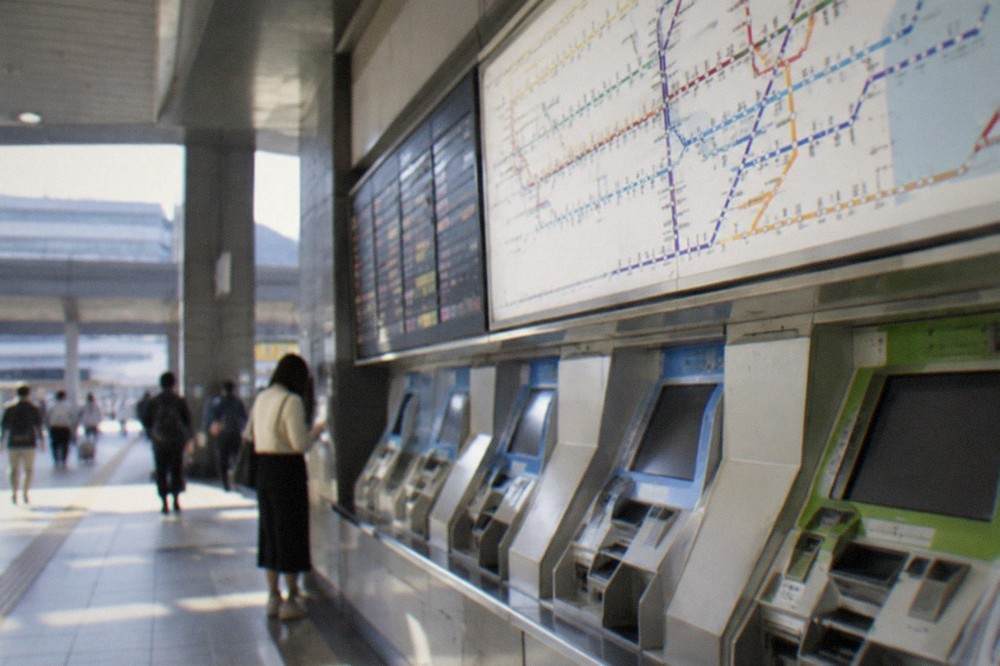 A train ticket machine and fare board inside a Japanese airport station concourse