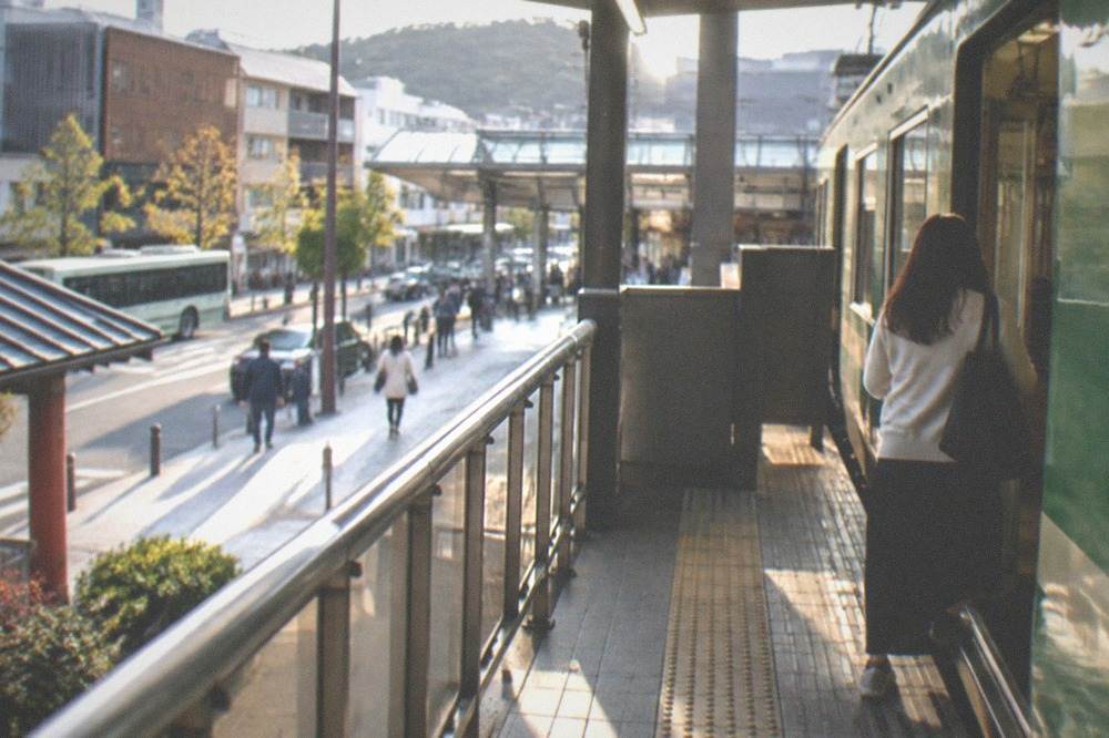 A passenger boarding a green Kyoto city bus through the front door