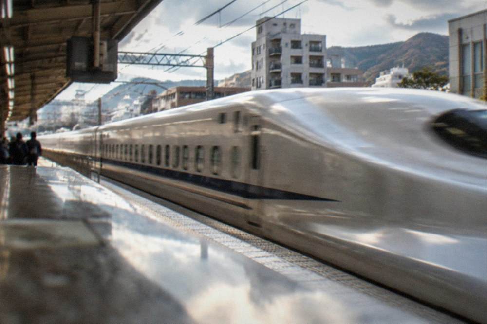 A high speed Shinkansen train passing through a station platform