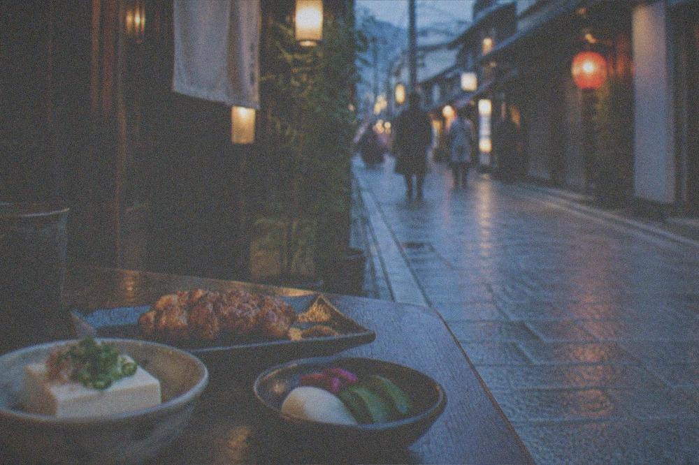 Small plates of tofu, grilled chicken and pickles arranged on a dark wooden table