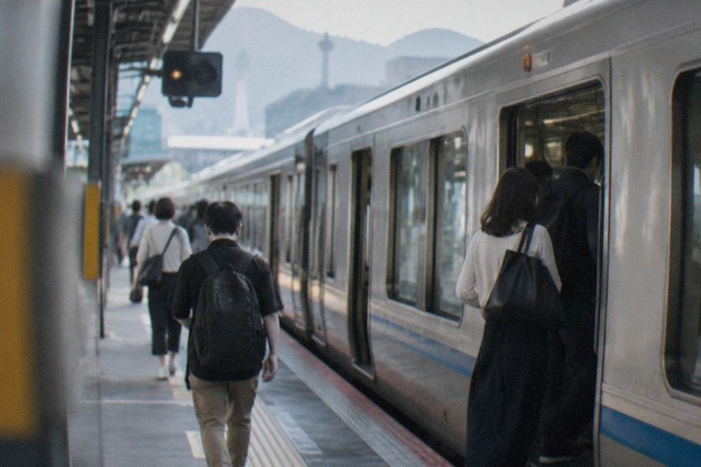 A JR local train waiting at a platform in Kyoto Station with passengers boarding