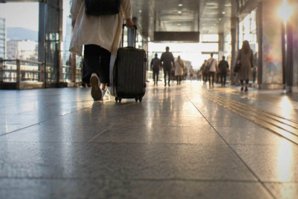 A traveller pulling a suitcase through a bright subway station corridor in Kyoto