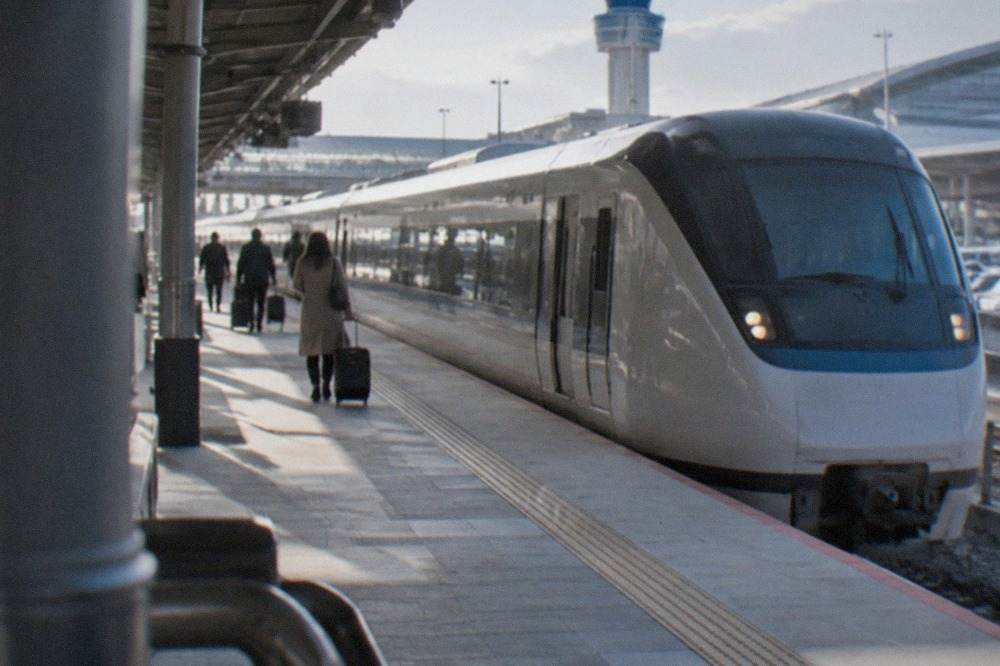 A limited express train standing at a station platform beside an airport terminal