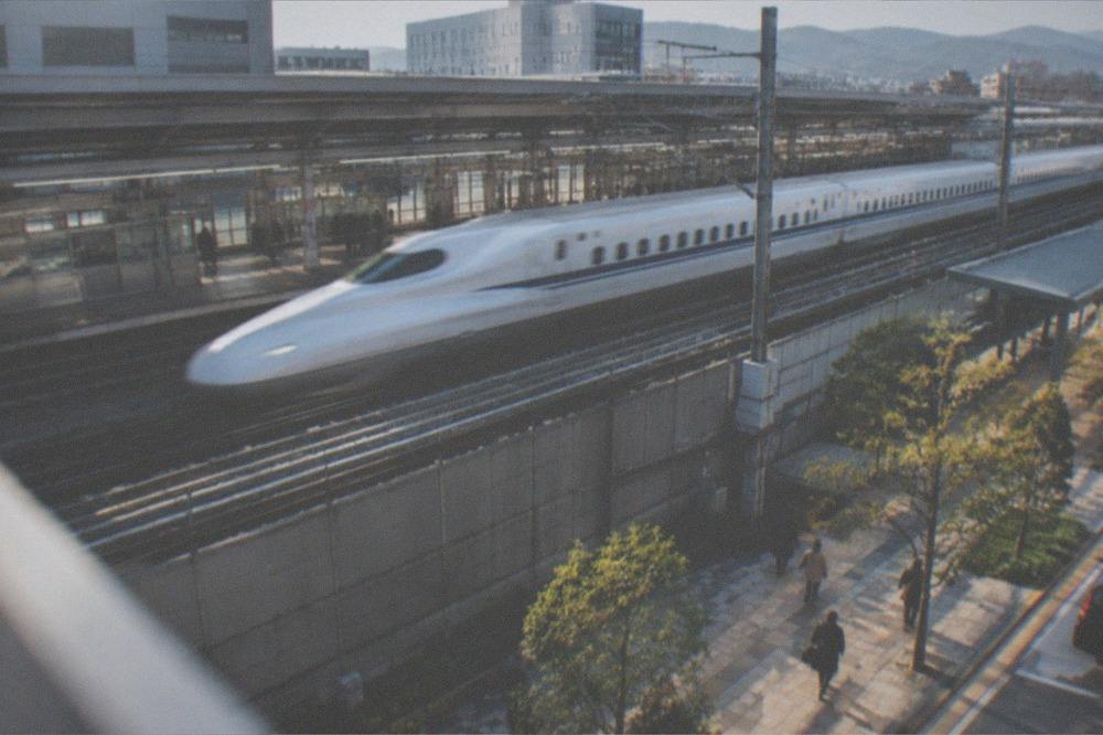 A high-speed bullet train passing through a station at speed