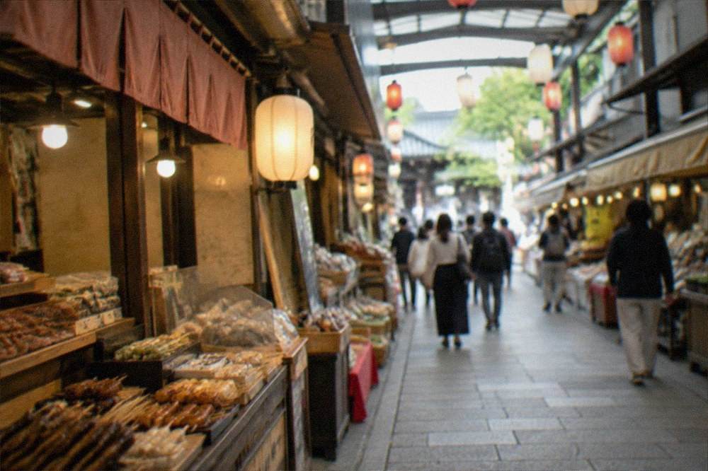 A covered market lane with food stalls on both sides and lanterns overhead
