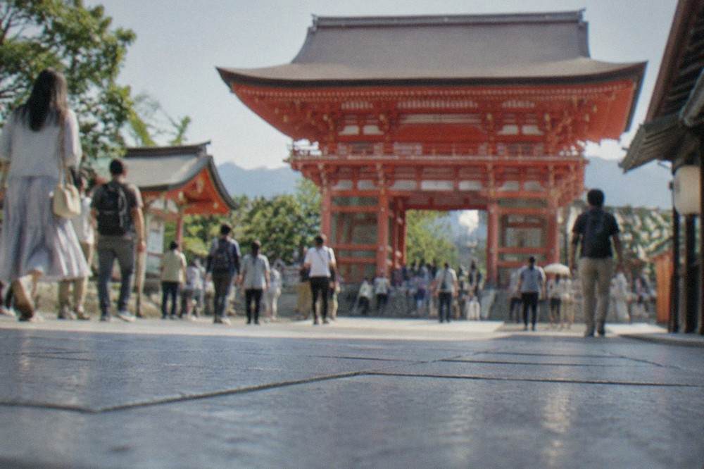 A smooth stone plaza in front of a large red shrine gate under a clear sky