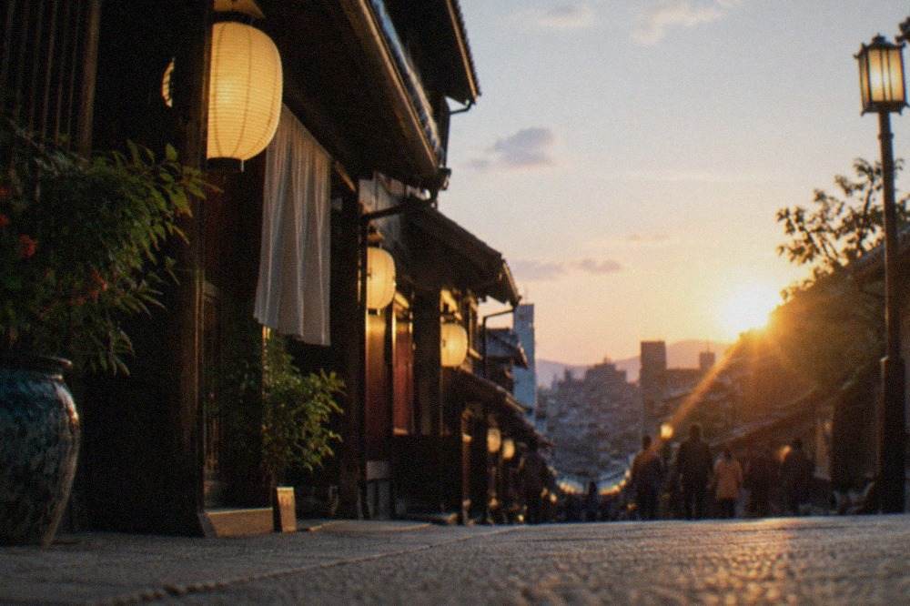A lantern-lit Kyoto street at dusk with traditional wooden machiya facades