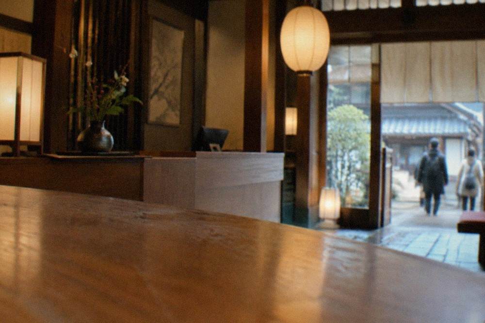 A reception desk in a Kyoto ryokan with a wooden counter and paper lanterns