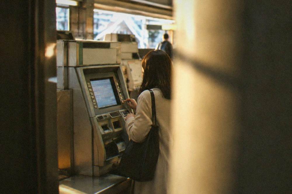 A ticket machine inside a Kyoto subway station with a passenger selecting a fare