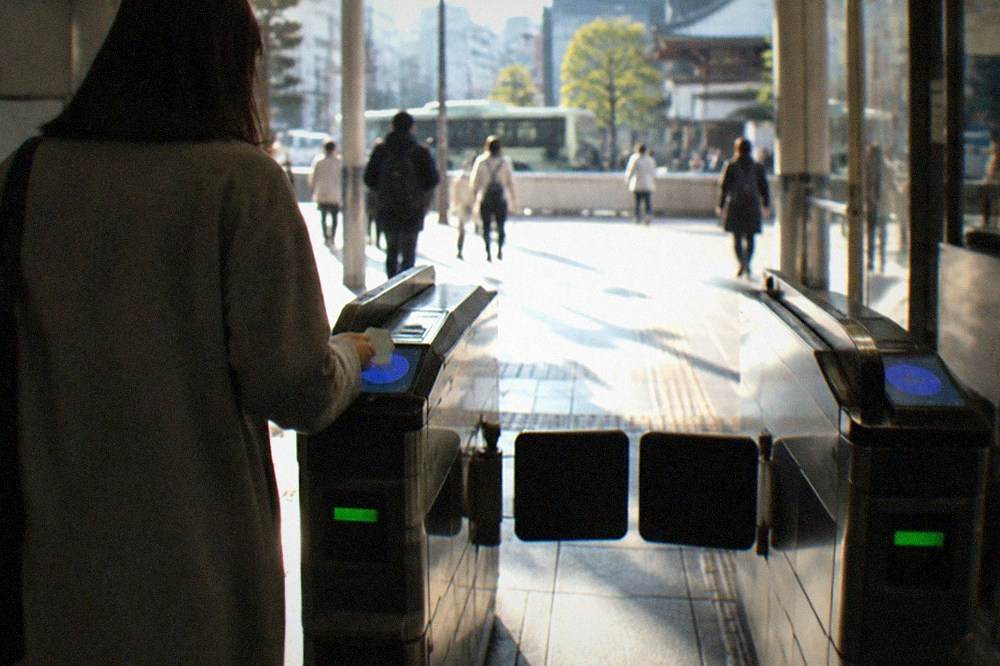 A subway station ticket gate in Kyoto with a passenger tapping an IC card