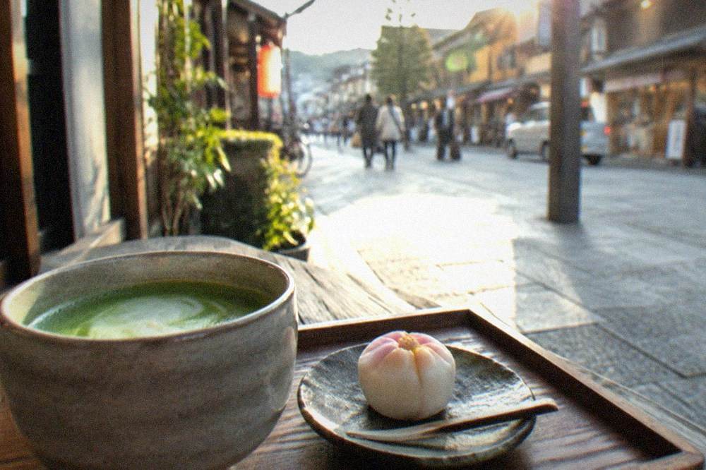 A matcha latte in a ceramic cup beside a wagashi sweet on a wooden tray