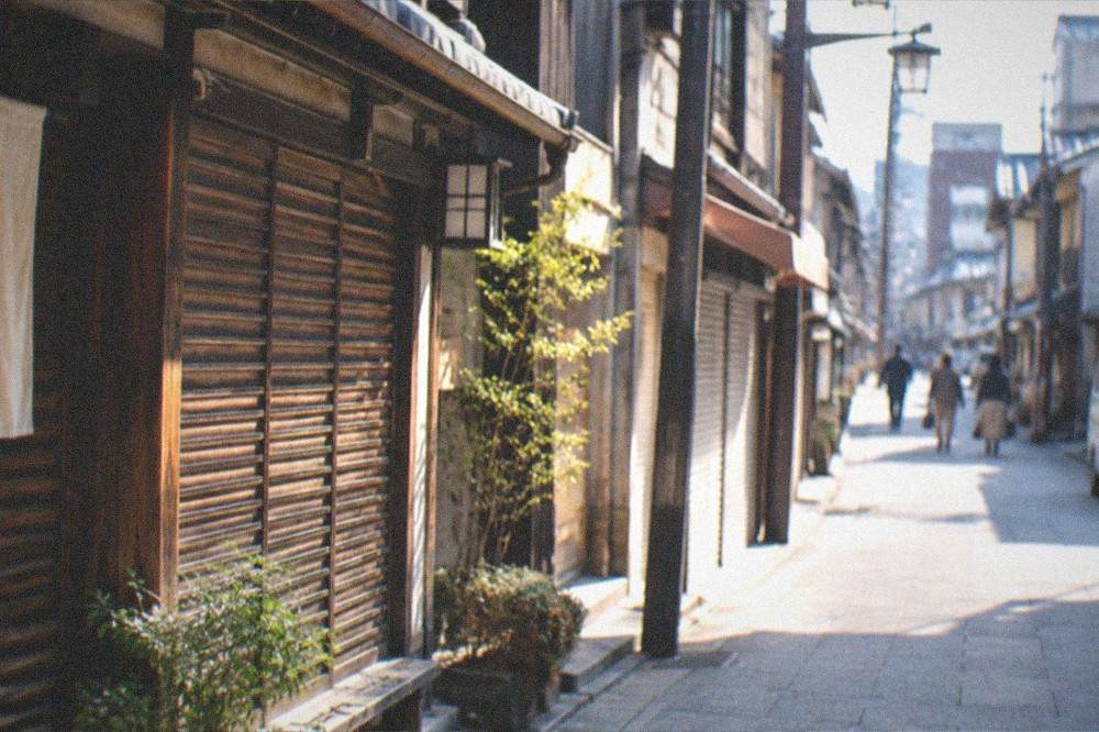 A quiet Kyoto side street in early morning light with closed wooden shutters