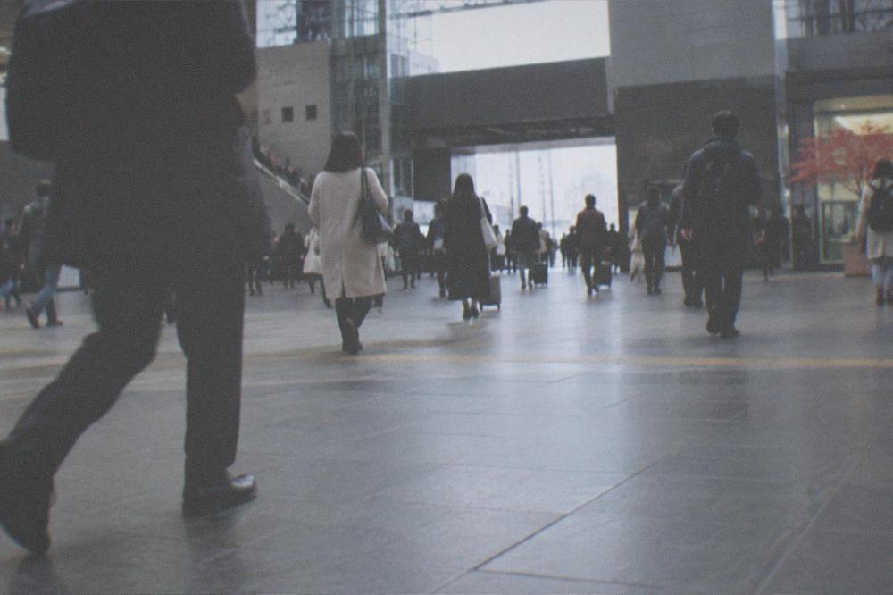 Commuters and visitors walking through the wide concourse of Kyoto Station in the morning