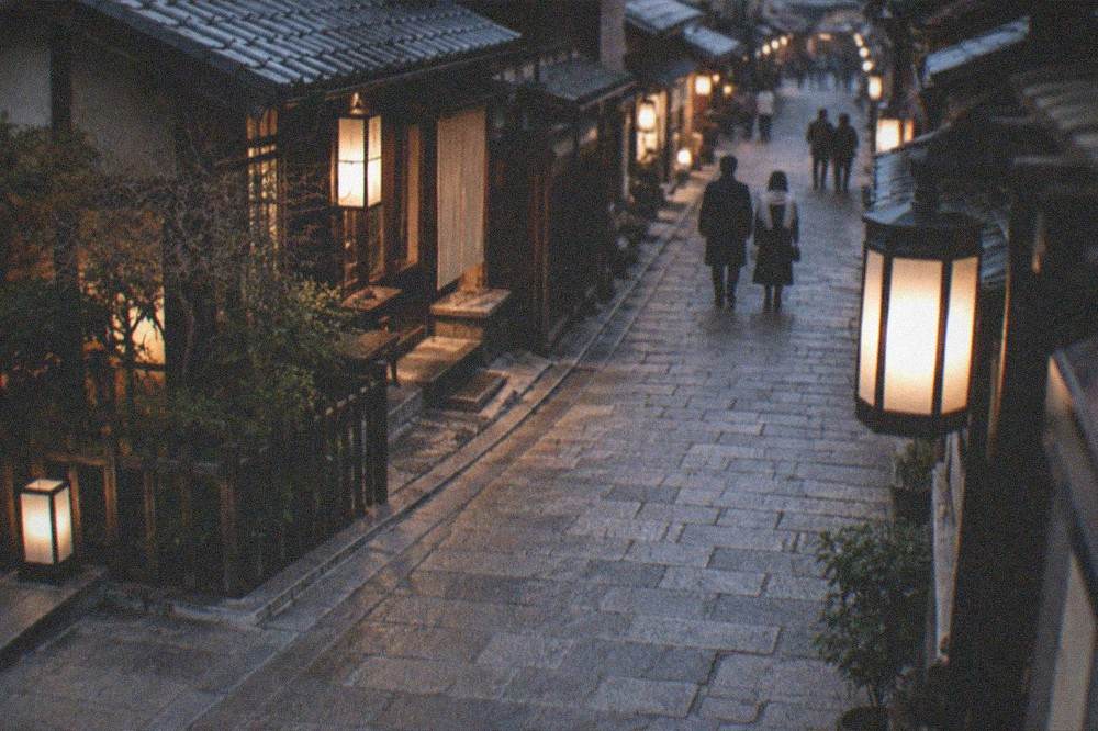 A calm evening scene of lanterns lighting a stone street in the Gion district after the day crowds have gone
