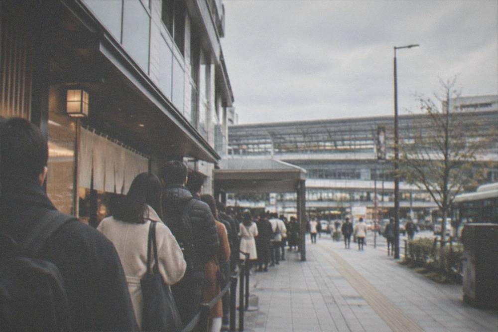 Passengers queuing in an orderly line at a Kyoto city bus stop