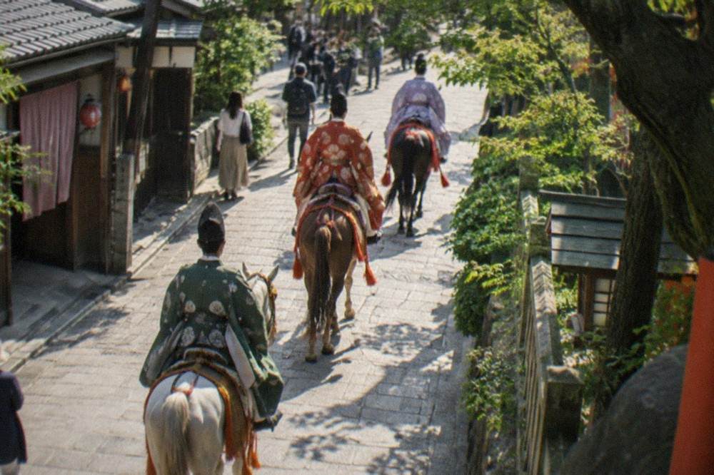 Horseback riders in Heian period costume on a tree lined Kyoto road