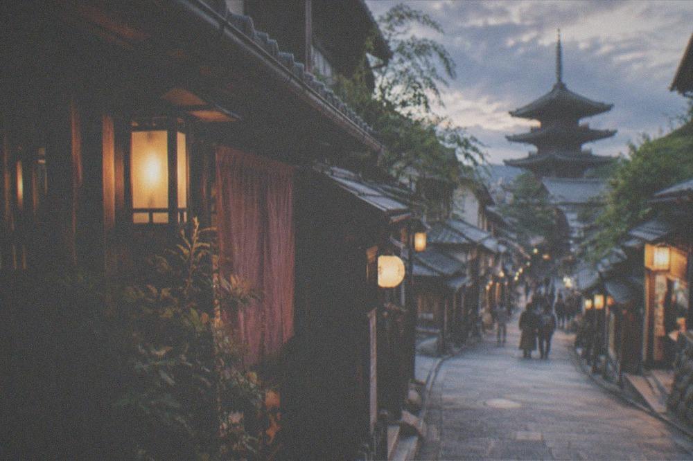 A lantern lit Kyoto alley at night with wooden machiya facades